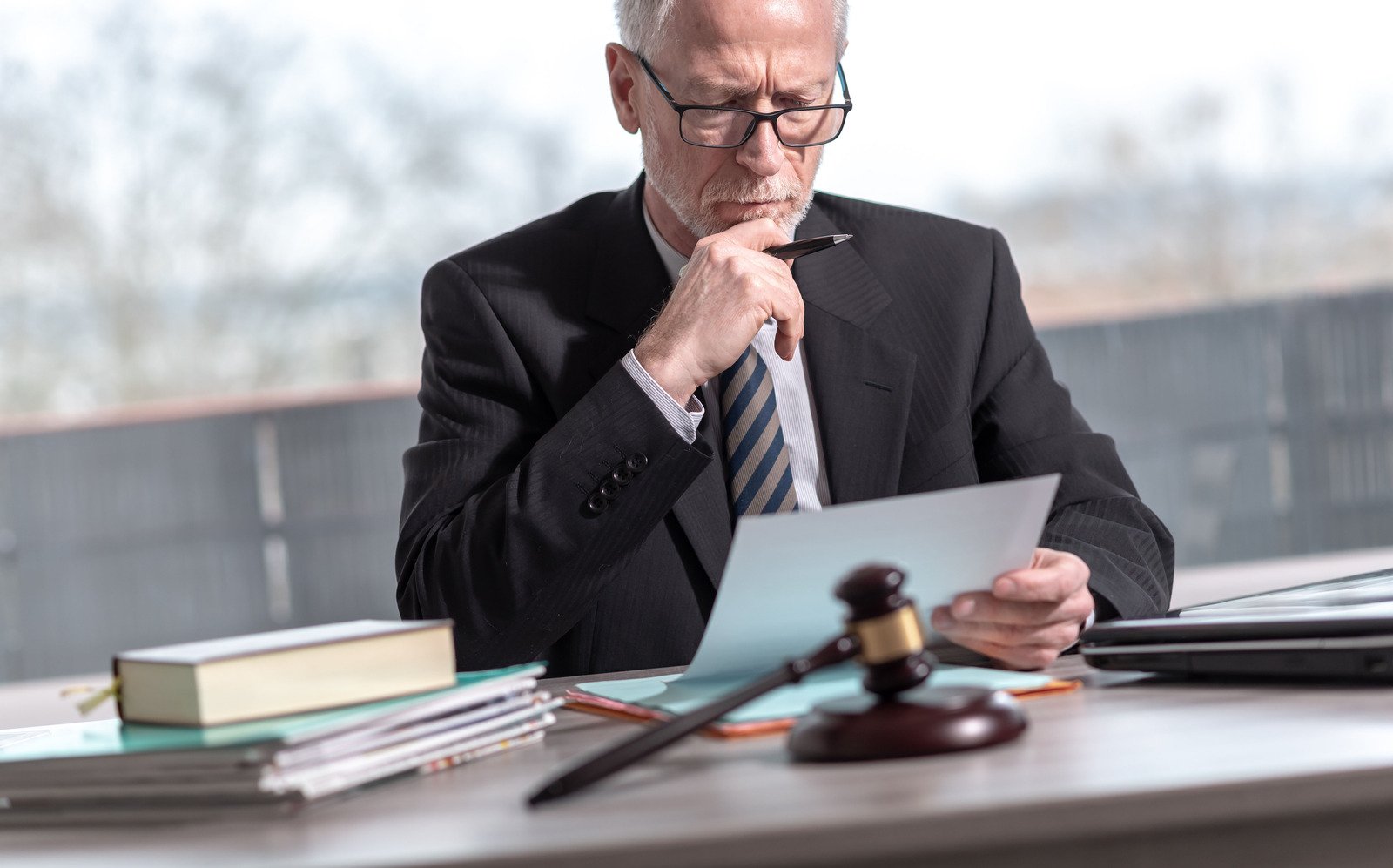 a man looking very serious and intense as he reads a will at a desk
